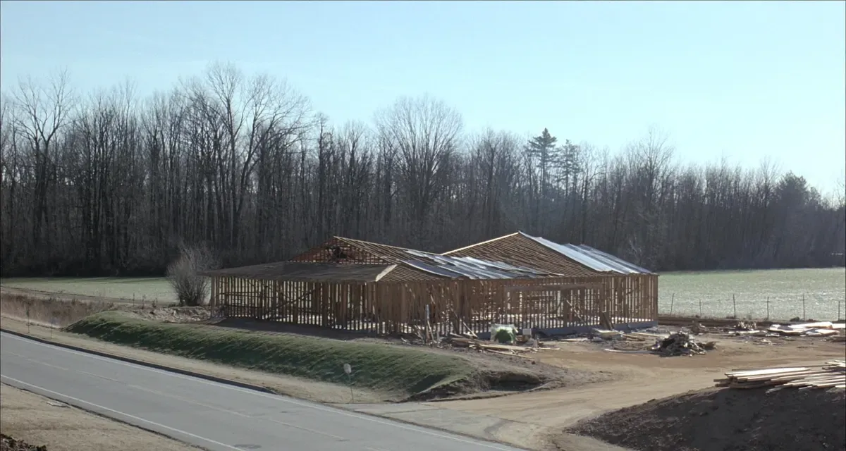Post-frame home under construction beside a paved county road in rural North Alabama