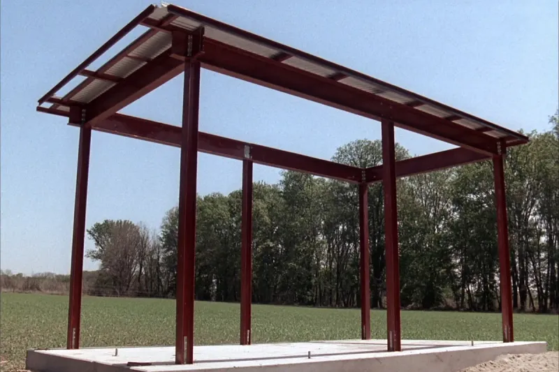 Red-iron steel building frame being erected on a concrete slab on North Alabama farmland